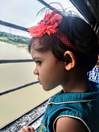 Side view of girl looking through window in train