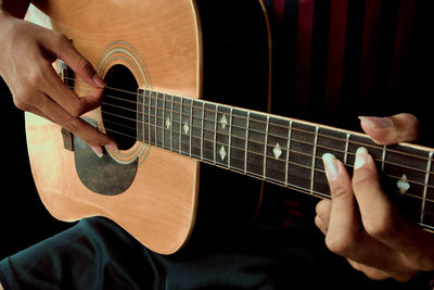 Midsection of man playing guitar