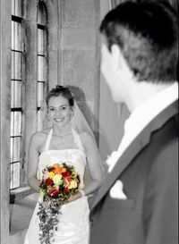 Woman holding flower bouquet against wall