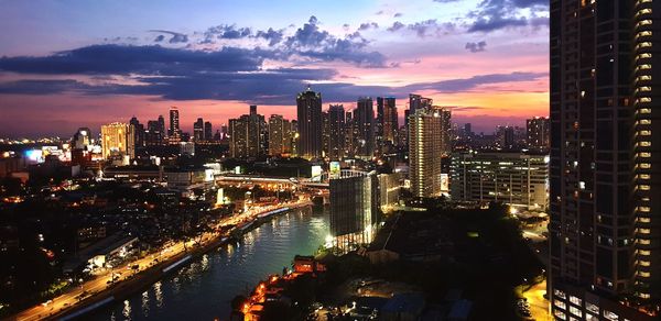 Aerial view of illuminated city buildings against sky during sunset