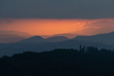 Scenic view of silhouette mountains against orange sky