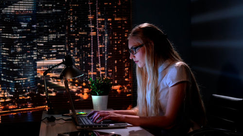 Portrait of young woman using mobile phone while sitting at airport