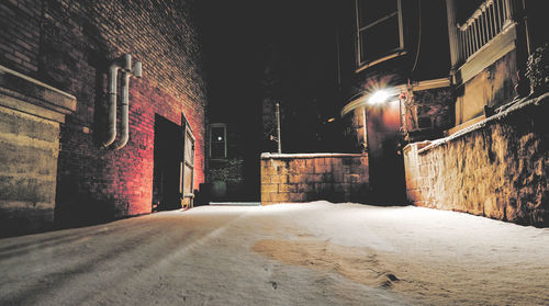 Empty road amidst buildings in city at night