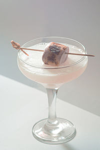 Close-up of martini coupes cocktail with marshmallow on white background