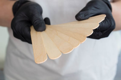 A young woman holding many wax wooden spatulas.