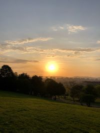 Scenic view of grassy field against sky during sunset