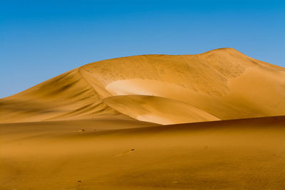 Scenic view of desert against clear blue sky