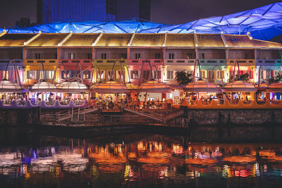 Illuminated building by river at night