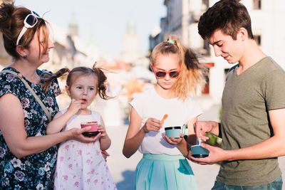 Mother and children having ice cream in city during sunny day