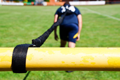 Full length rear view of man tied with rope walking on field