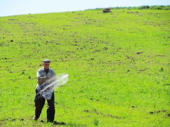 Senior man sprinkling fertilizers on farm