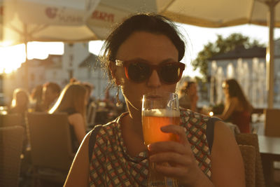 Mature woman drinking beer in restaurant during sunset