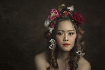 Portrait of beautiful young woman against black background