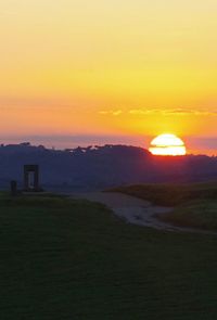 Scenic view of field against orange sky