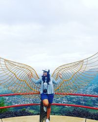 Woman standing at railing against sky