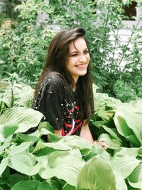 Young woman smiling while standing against plants