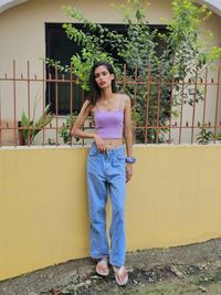 Young woman standing against wall