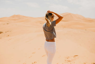 Woman standing on sand dune in desert