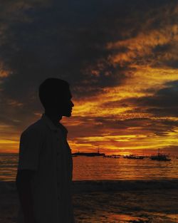Silhouette man looking at sea against sky during sunset
