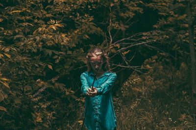 Girl holding branch while standing in forest