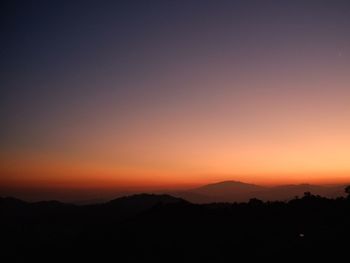 Scenic view of silhouette mountains against orange sky