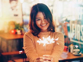 Smiling young woman holding sparklers