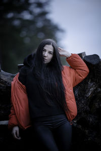 Young woman looking away while sitting on tree