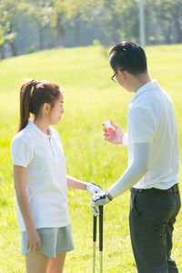 Full length of couple playing golf on field