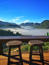 Chairs and tables by lake against sky