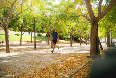 Rear view of man running on footpath in park