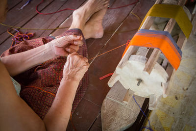 Low section of woman weaving thread