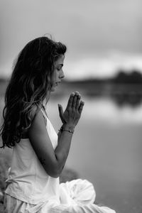 Full length of woman doing yoga while sitting on pier at lake