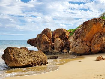 Rocks on shore by sea against sky