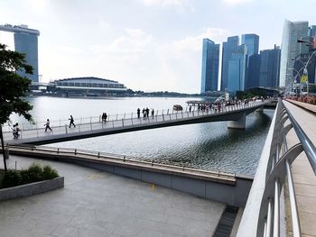 Bridge over river by buildings against sky