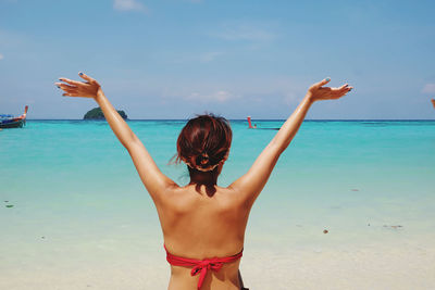 Rear view of woman standing at beach against sky