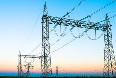 Low angle view of electricity pylon against sky during sunset