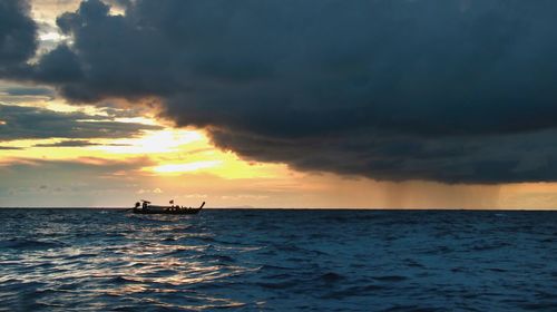 Silhouette people on sea against sky during sunset