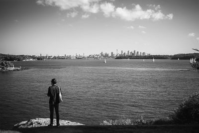 Rear view of man standing on beach against sky