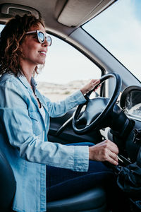 Side view of woman driving car