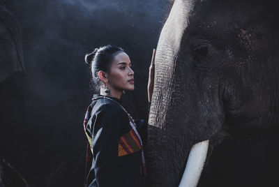 Smiling woman standing with elephant in forest