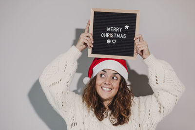 Smiling woman with merry christmas text at home