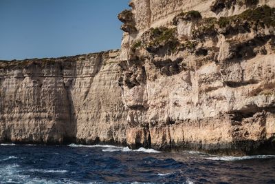 Rock formations by sea against sky