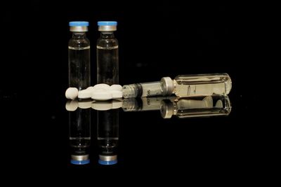 Close-up of pills with bottles against black background