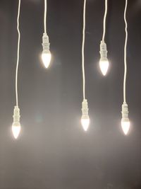 Low angle view of illuminated light bulbs hanging from ceiling