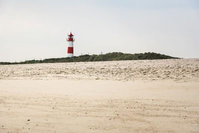 Lighthouse by sea against sky