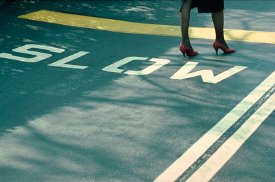 Low section of woman standing on road sign