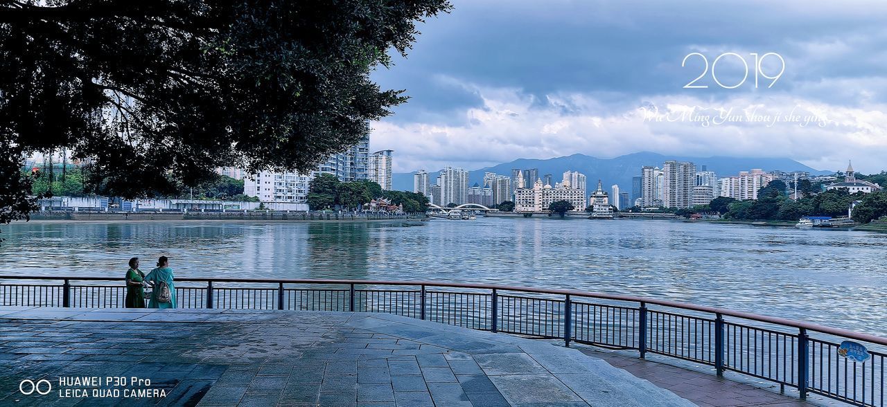 RIVER AMIDST BUILDINGS IN CITY AGAINST SKY