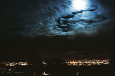 Silhouette of trees against dramatic sky at night