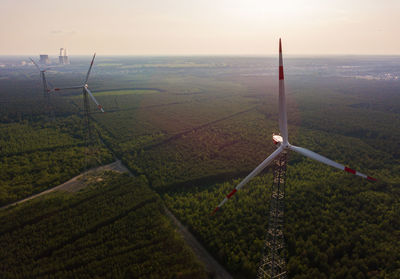 Scenic view of wind turbines agricultural field against sky. renewable energy
