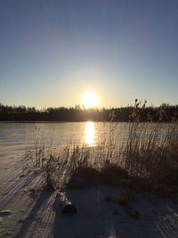 Scenic view of frozen lake against clear sky during sunset
